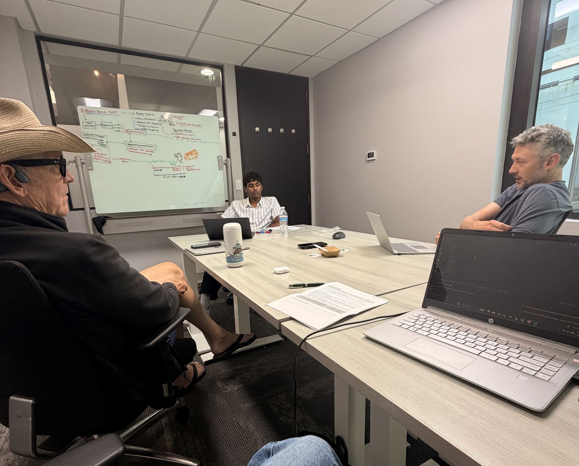 Team members review the medical-records pipeline sketch on the whiteboard during a working session in San Diego.